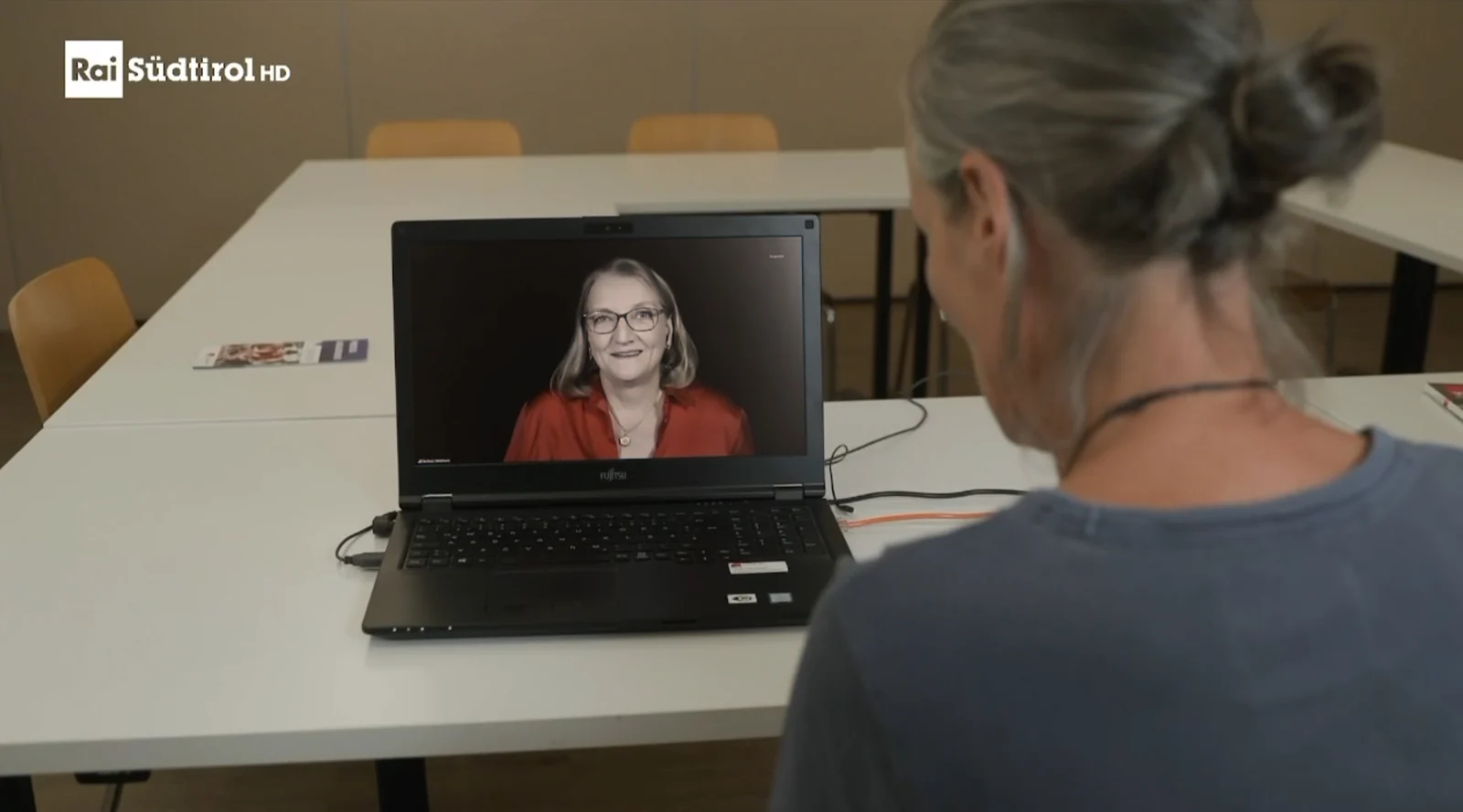 Eine Frau blickt auf einen Laptop, auf dem Barbara Weidmann-Lainer im zugeschalteten RAI-Interview zu sehen ist.